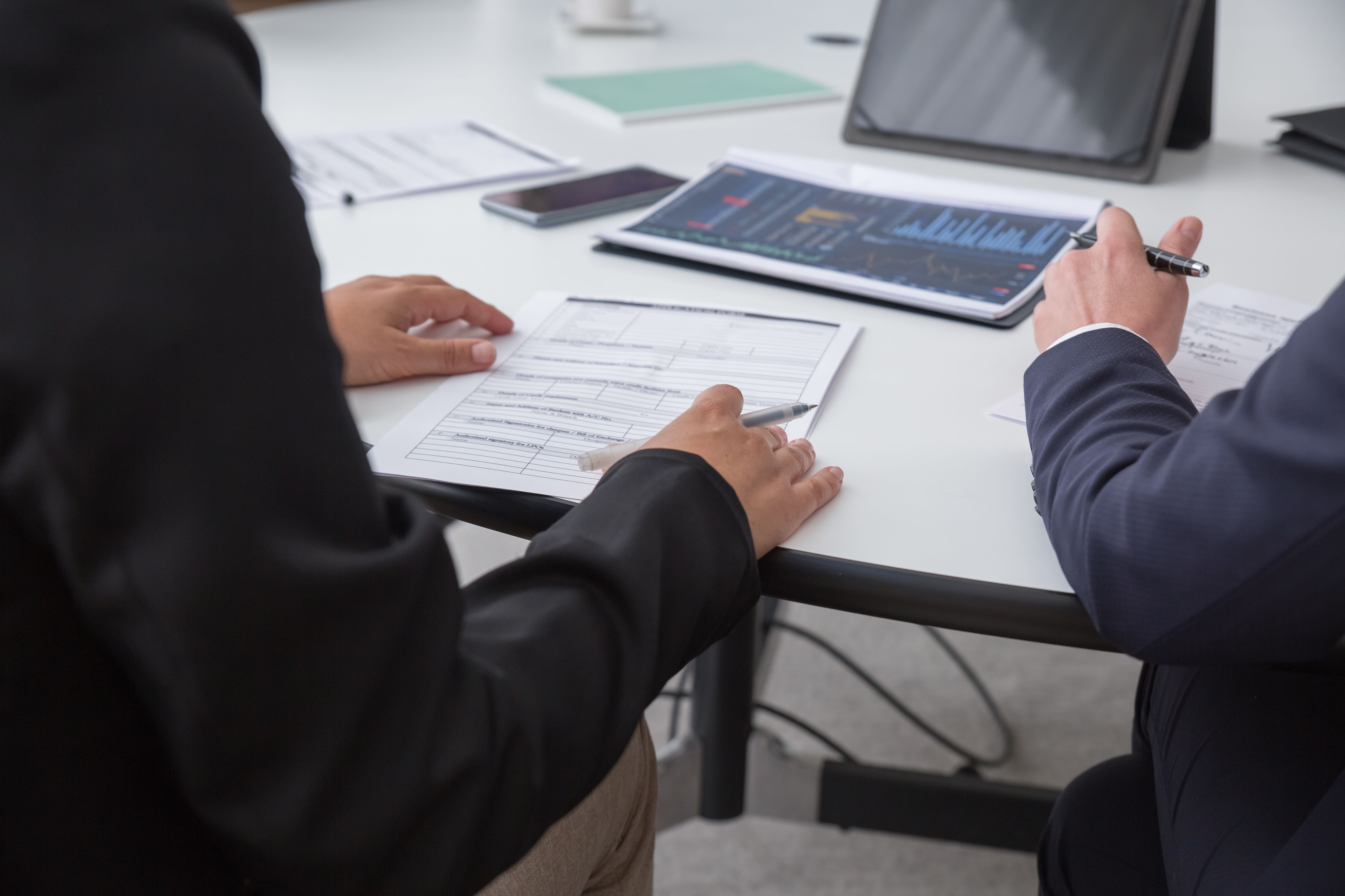 Financial documents and charts spread across a table during a planning meeting